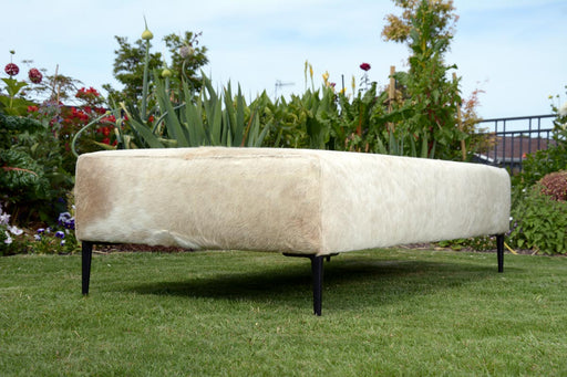 Beige cowhide ottoman with black legs