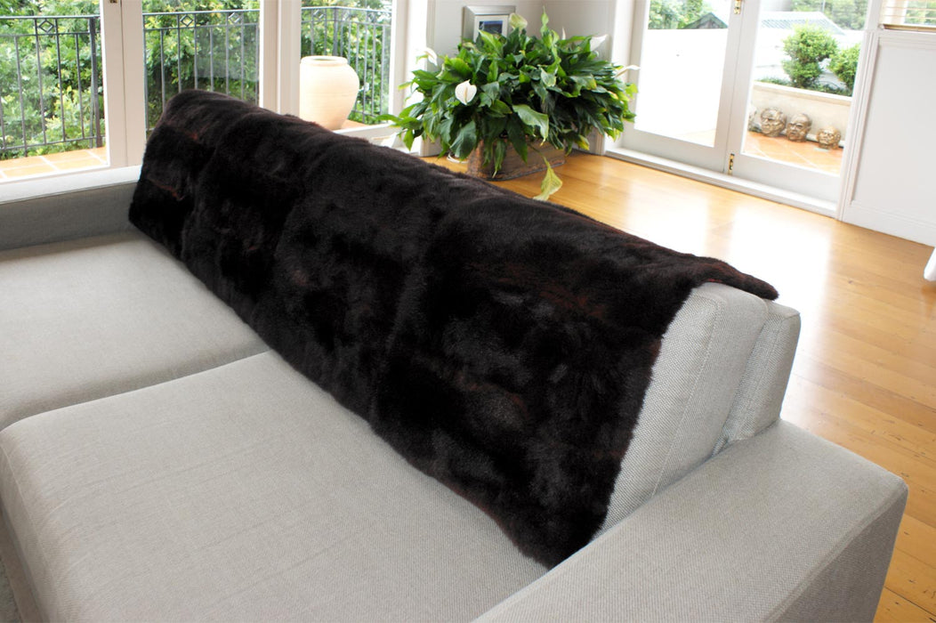 NZ Possum Fur Throws Warm Black over the back of a sofa
